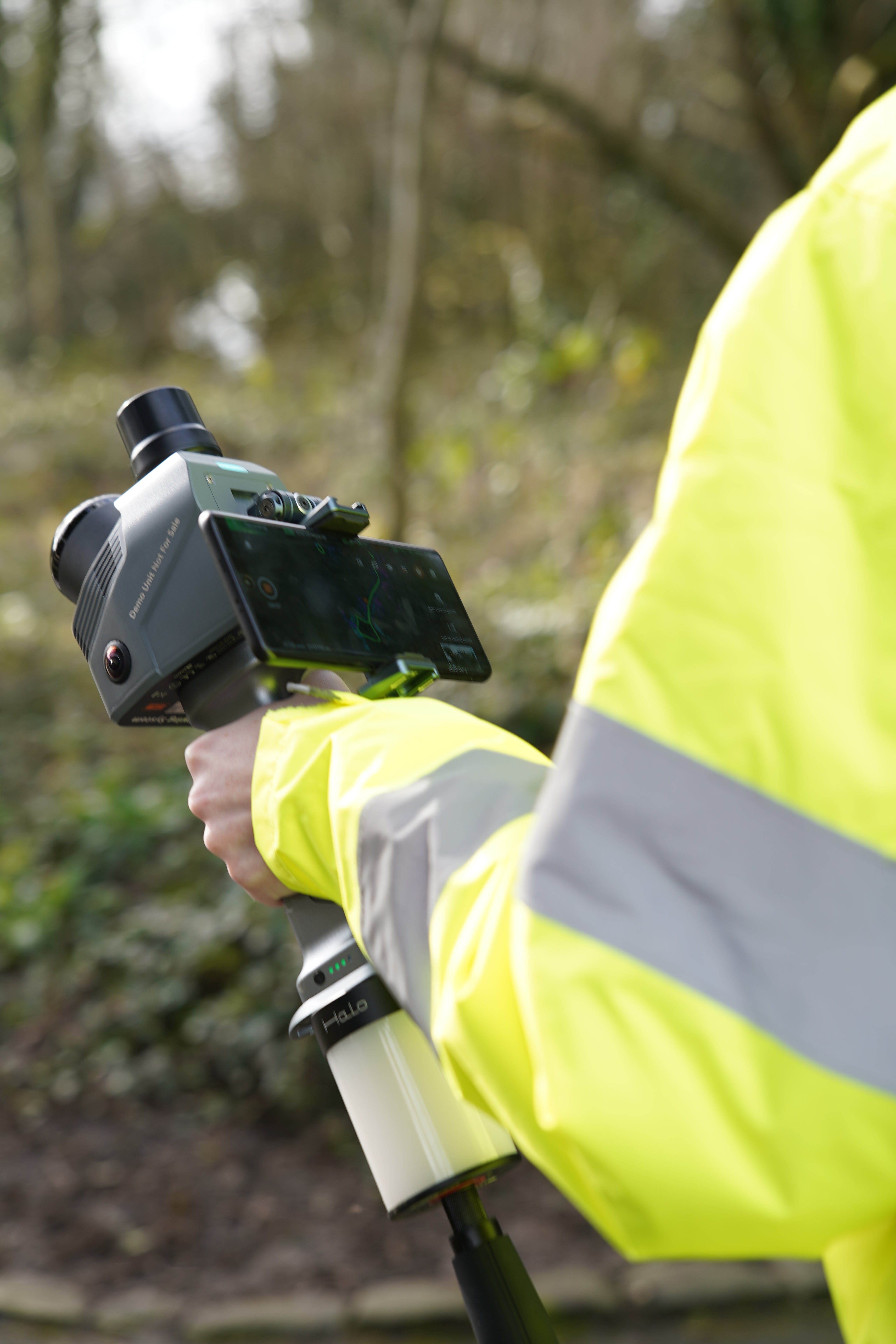 Person wearing a high-visibility jacket holding a CHCNAV RS7 with a blurred natural background